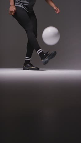 Vertical-Video-Close-Up-Of-Female-Footballer-Training-In-Vertical-Video-Studio-Playing-Keepy-Uppy-Kicking-Ball